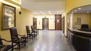 A reception area with a counter, two elevators, and a row of leather chairs. - JOIVY Lovely Apt On The Historical Street Via Cantore (Genoa)