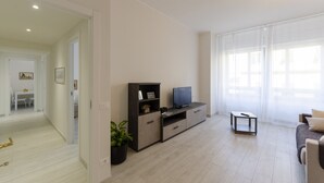 A modern living room with a TV, a small table, and a sofa. - JOIVY Lovely Apt On The Historical Street Via Cantore (Genoa)