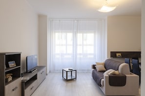 A modern living room with a flat-screen TV, a sofa, a coffee table, and a TV stand.