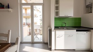 A modern kitchen with white cabinets, a green backsplash, and a dishwasher. - JOIVY Spacious Family Flat For 6 People In Genova (Genoa)