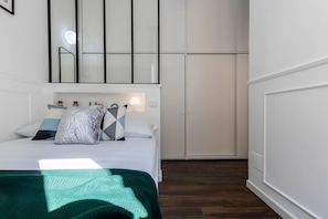 A bedroom with a bed, pillows, a nightstand, a mirror, and a wardrobe. - JOIVY Chic Apartment For 3 Close To Sempione Park (Milan)
