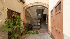 An outdoor area with a brick archway leading to a staircase, potted plants, and bicycles. - JOIVY Charming Flat Next to Duomo di Como (Como)