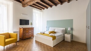 A bedroom with a bed, bedside tables, a dresser, a chair, and a TV on the wall. - JOIVY Charming Flat Next to Duomo di Como (Como)