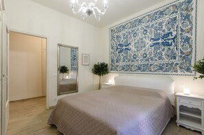 A bedroom with a large bed, a mirror, a nightstand with a lamp, and a wall tapestry. - JOIVY Lovely Apt For 4 On The Italian Riviera In Rapallo (Rapallo)