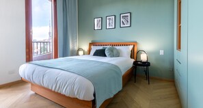 A bedroom with a large bed, a nightstand with a lamp, and three framed pictures on the wall. - JOIVY Superb Apt Close To Fiera Milano And City Life (Milan)