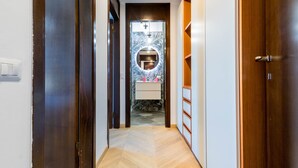 Ein Flur, der zu einem Badezimmer mit Spiegel, Waschbecken und Toilette führt.