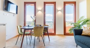 A dining area with a table and chairs, a television mounted on the wall, and a balcony with a view. - JOIVY Superb Apt Close To Fiera Milano And City Life (Milan)