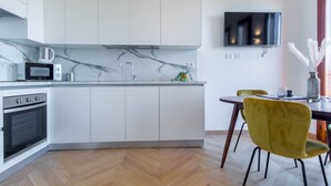Eine moderne Küche mit weißen Schränken, einer Mikrowelle, einem Wasserkocher und einem Essbereich mit Tisch und Stühlen.