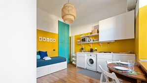 A compact room with a bed, a washing machine, and a dining area. - JOIVY Bright And Cozy Studio For 2 In Porta Genova (Milan)
