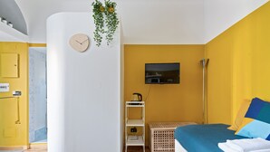 A modern bedroom with a bed, a TV, a clock, and a plant. - JOIVY Bright And Cozy Studio For 2 In Porta Genova (Milan)