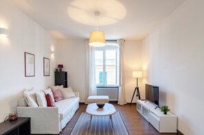 A modern living room with a sofa, a coffee table, a TV, and a lamp.
