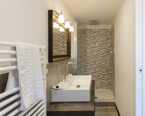 A bathroom with a white sink, a mirror, and a shower.