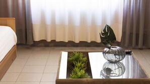 Ein Hotelzimmer mit einem Bett, einem Glastisch mit Pflanze und Vase sowie einer Fernbedienung auf dem Tisch.