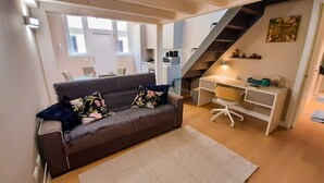 Un espace de vie moderne comprenant un canapé, un bureau et un escalier.