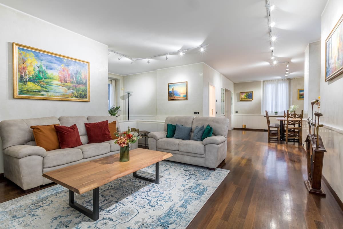 Uma sala de estar ampla com dois sofás, uma mesa de centro e um espaço de jantar com cadeiras e mesa.