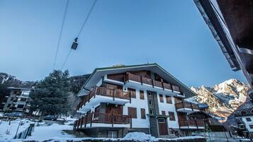 A multi-story hotel with balconies, a ski lift in the background, and snow-covered surroundings.