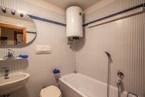 A bathroom with a sink, toilet, bathtub, and a mirror. - JOIVY Family Apartment, near Ski Lifts, In Courmayeur (Courmayeur)