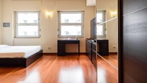 A modern bedroom with a wooden floor, a bed, a desk, and a TV. - JOIVY Bright Studio For 2 Close To Milano Centrale (Milan)