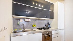 A modern kitchen with white cabinets, a stainless steel sink, a gas stove, and a built-in oven. - JOIVY Lovely Flat For 4 W/Balcony Near Porta Romana (Milan)