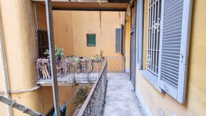 Un balcone stretto con ringhiera metallica, piante in vaso e una bicicletta.