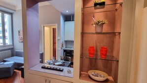 Un soggiorno moderno con un divano grigio, un tavolino con un portatile e una vetrina contenente oggetti decorativi.