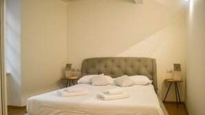 Un lit bien fait, avec du linge de lit blanc et des oreillers, deux tables de chevet avec des lampes et une tête de lit moderne.