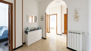 A hallway with a white dresser, a mirror, and a radiator. There is a wooden door frame and a light fixture on the wall. - JOIVY Family Flat W/Terrace & Parking Near Beach (Sestri Levante)