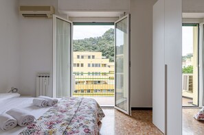 A hotel room with a bed, a window with a view of buildings, and a radiator. - JOIVY Family Flat W/Terrace & Parking Near Beach (Sestri Levante)