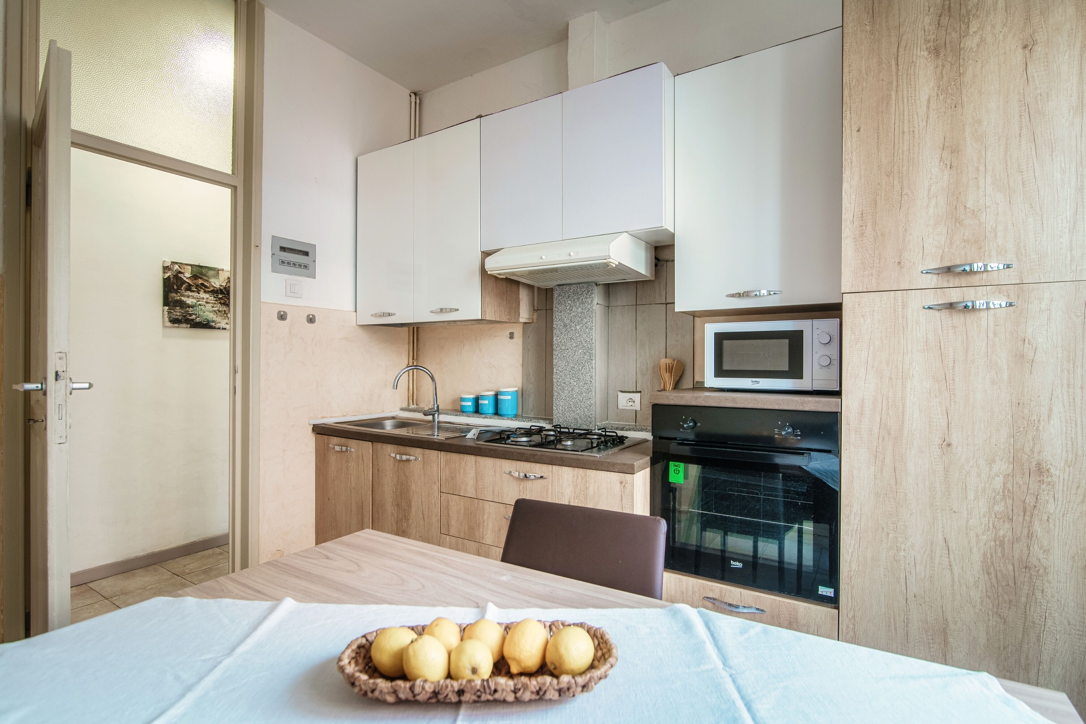 Une cuisine moderne avec des meubles blancs, une cuisinière à gaz, un four et un four à micro-ondes.
