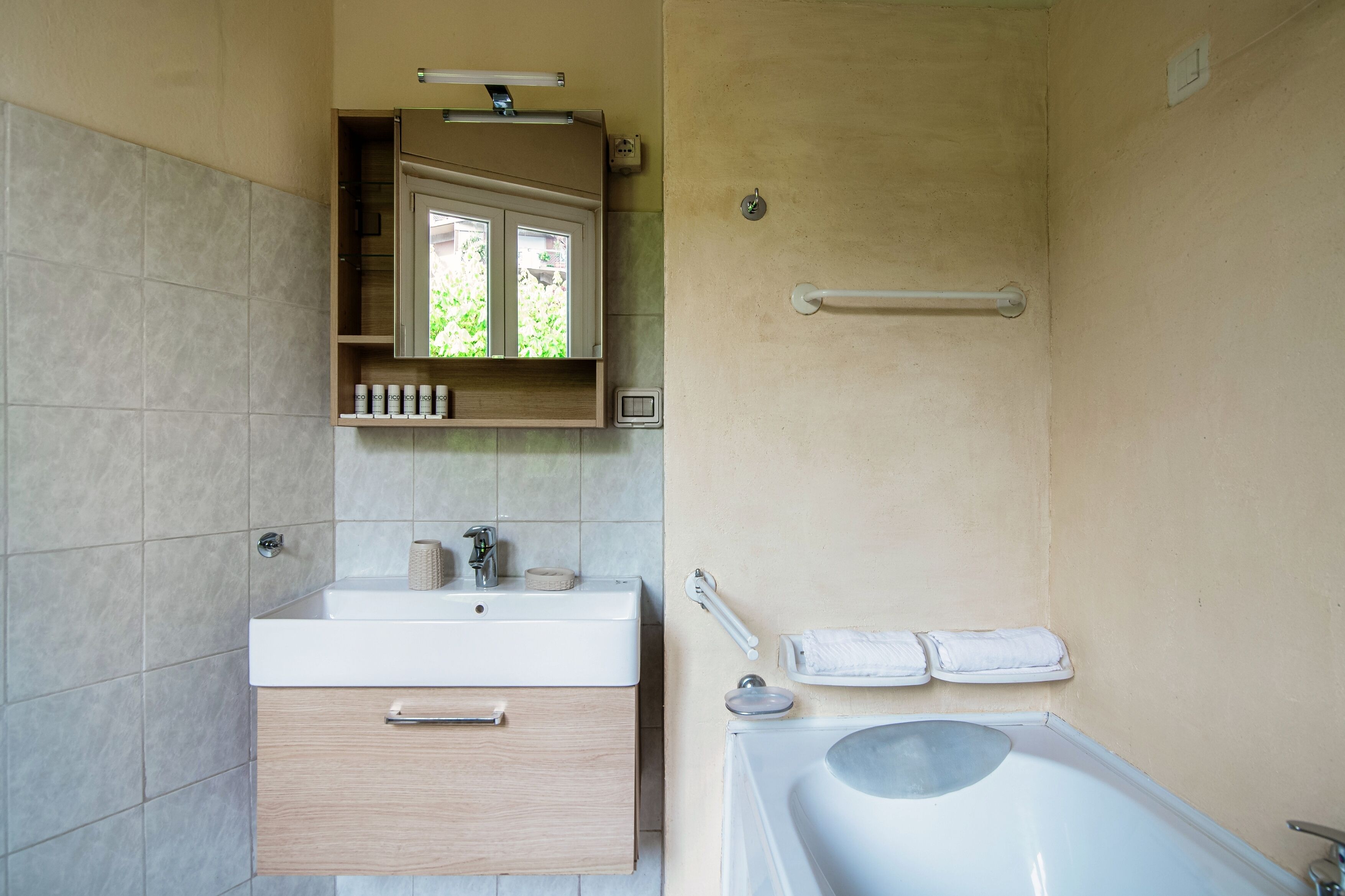 A bathroom with a sink, mirror, towel rack, and bathtub.