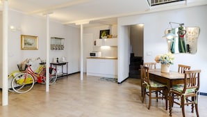 A spacious living area with a wooden dining table, chairs, and a red bicycle. - JOIVY Superb Flat Near Ch. Columbus' House (Genoa)