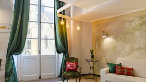 A room with a large window, a green chair, a white sofa, and a small table with a plant. - JOIVY Superb Flat Near Ch. Columbus' House (Genoa)