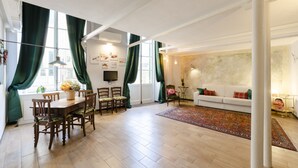 A spacious living area with a dining table, chairs, a sofa, and a patterned rug. - JOIVY Superb Flat Near Ch. Columbus' House (Genoa)