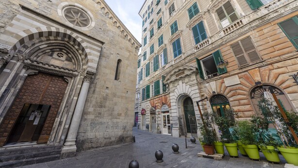 A narrow street with historic buildings, including a church with a large wooden door and a building with green shutters. - JOIVY Superb Flat Near Ch. Columbus' House (Genoa)