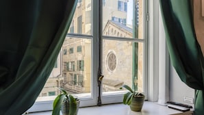 A window with green curtains, two potted plants, and a remote control on a windowsill. - JOIVY Superb Flat Near Ch. Columbus' House (Genoa)