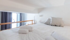 A hotel room with a large bed, a wooden headboard, and a balcony with curtains.