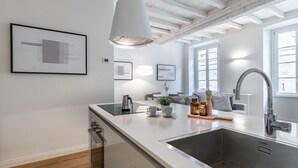 A modern kitchen with a large island, stainless steel sink, and pendant lighting.