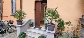 A staircase leading to a door, flanked by potted plants and a bicycle. - JOIVY Modern Studio Near City Centre (Milan)