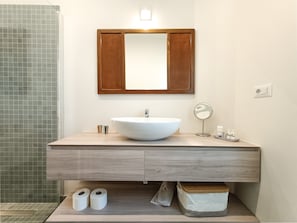 A bathroom with a large white sink, a wooden cabinet below, and a mirror above.