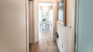 A hallway leading to a dining area with a table and chairs, a radiator, and a mounted television. - JOIVY Bright Flat W/2 Balconies & Sea View (Alassio)