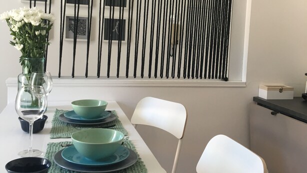 A dining table set with green plates, a glass vase with flowers, and a wine glass. - JOIVY Stylish Apt in Centre of Cernobbio (Cernobbio)