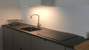 A modern kitchen with a stainless steel sink, a black countertop, and a wire basket. - JOIVY Stylish Apt in Centre of Cernobbio (Cernobbio)