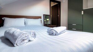 A neatly made bed with rolled white towels, a wooden headboard, a mirror, and a green wardrobe. - JOIVY Stylish Flat, 5-Minute Metro Trip To Centre (Milan)