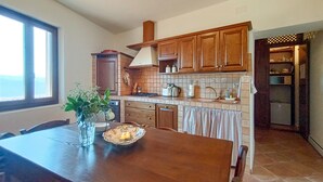 Eine Küche mit Holzausbau, einer gefliesten Spritzschutzwand, einem Esstisch mit Stühlen und einem Fenster, das für natürliches Licht sorgt.