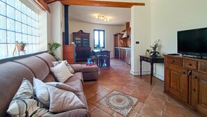 Ein Wohnzimmer mit einer Couch, einem Fernseher und einer Küche im Hintergrund.