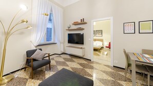 Un salon moderne avec un canapé, un téléviseur, une table à manger et un sol à motifs.