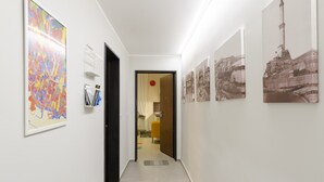 Un couloir dont les murs sont ornés d’œuvres d’art, une porte donnant sur une autre pièce et un sol carrelé.