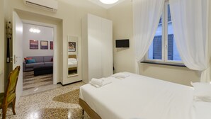 Une chambre d’hôtel avec un lit, une télévision, une armoire, un canapé et une fenêtre avec des rideaux.