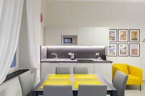 A modern kitchen with a microwave, kettle, and sink. There are framed pictures on the wall and a bright yellow chair. - JOIVY Bright Flat In The Perfect Centre Of Genoa (Genoa)