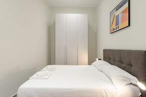 A bedroom with a bed, a wardrobe, and a painting on the wall. - JOIVY Bright Flat In The Perfect Centre Of Genoa (Genoa)